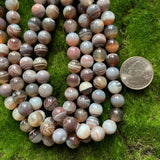 10mm smooth round Botswana agate bead strands on green background with US quarter for scale