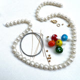 white pearl strand, red, orange, yellow, green, and blue mushrooms, gold beads, and stainless steel wire on a white background