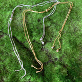 adjustable necklace chains in silver and gold on a green background