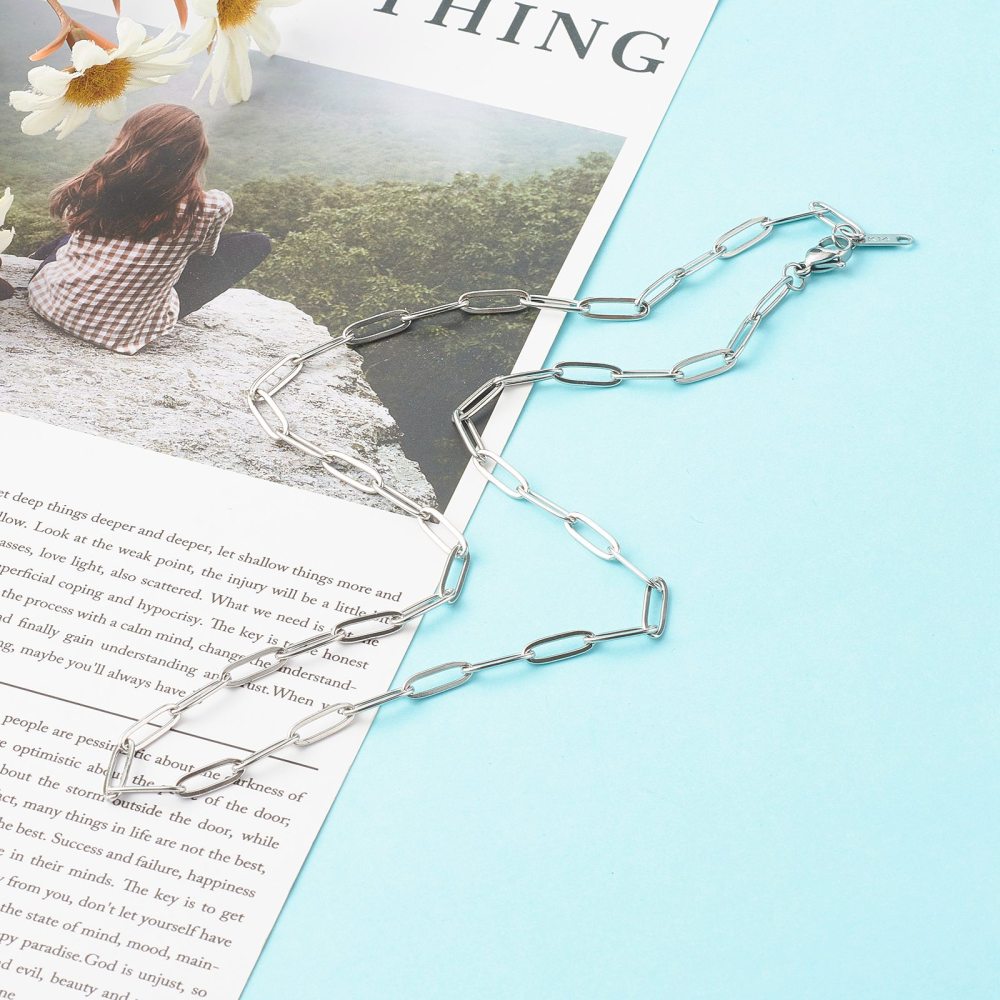 silver tone medium link paperclip chain necklace with lobster claw clasp on magazine article and light blue background. . 