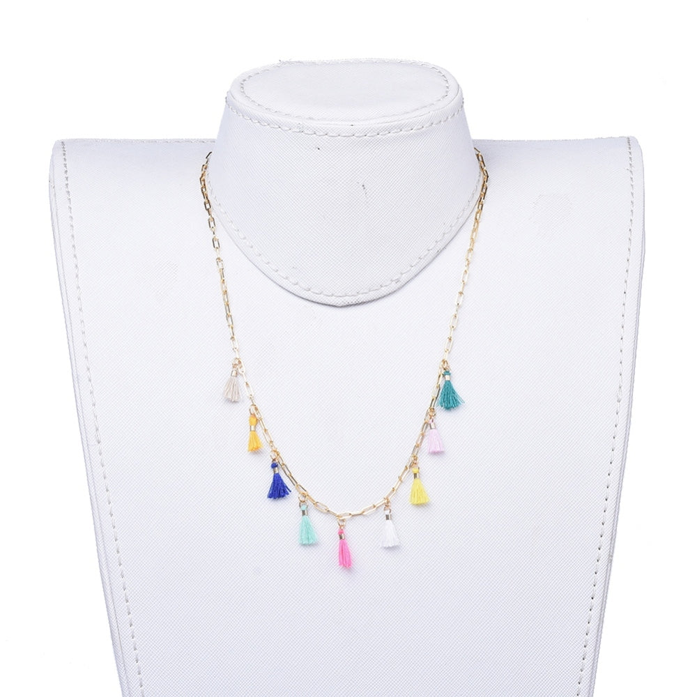 golden paperclip necklace with nine multi-colored tassel charms spaced evenly through the center and a lobster claw clasp and extender chain on white neck form with white background. 