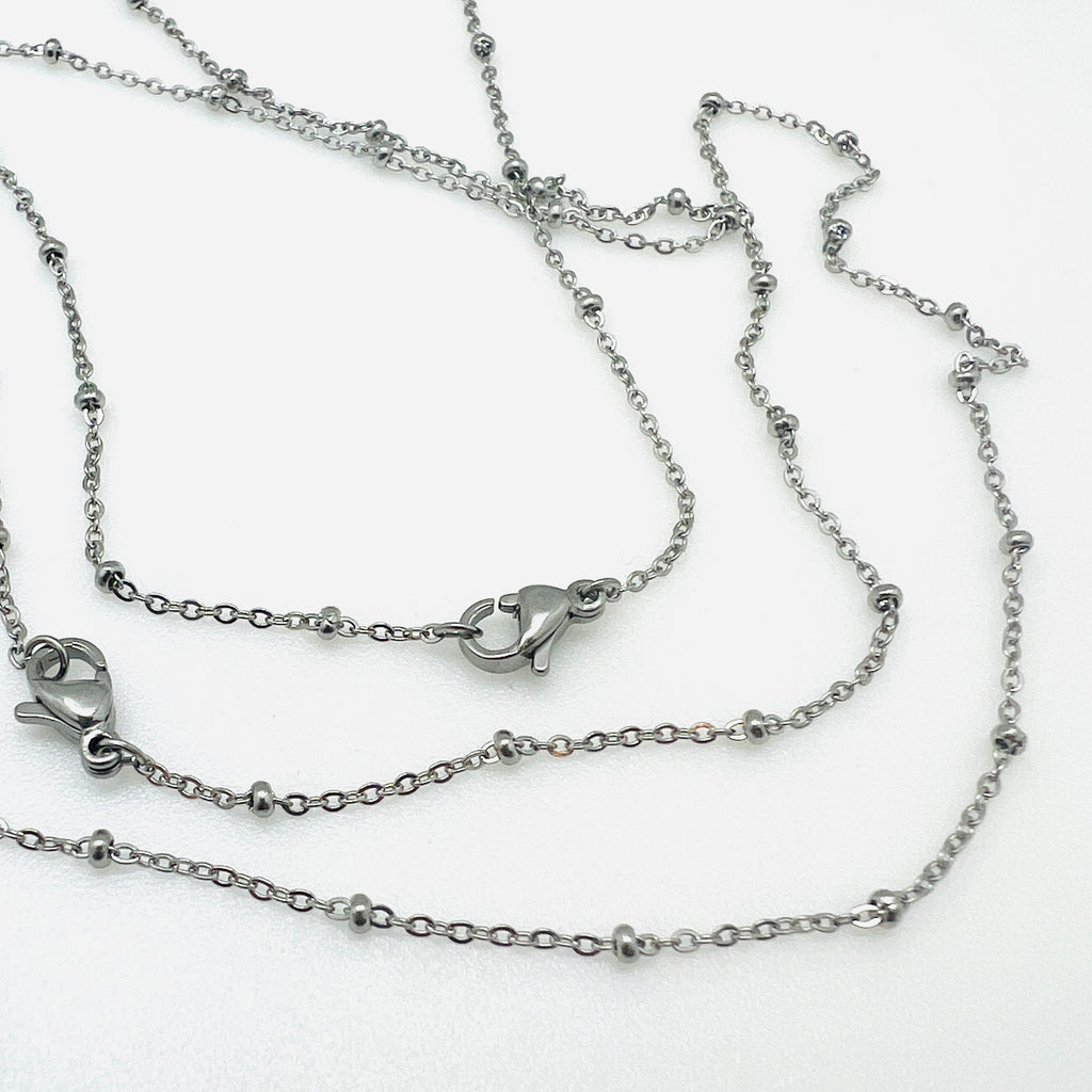 silver tone satellite chain necklace with rondelle beads and lobster claw clasp over white background. 