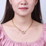 golden paperclip chain necklace with focal clear stone pave lobster claw clasp displayed on human neck with white background. 