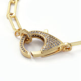 zoomed in clasped golden focal clear stone pave clasp and jump ring on paperclip chain with white background. 
