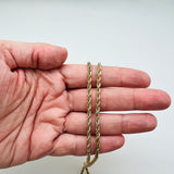 golden rope chain displayed on a hand with white background. 