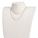 golden chain and multi-colored tourmaline faceted round beaded necklace on off-white neck form over white background. 