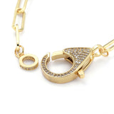 zoomed in unclasped golden focal clear stone pave clasp and jump ring on paperclip chain with white background. 