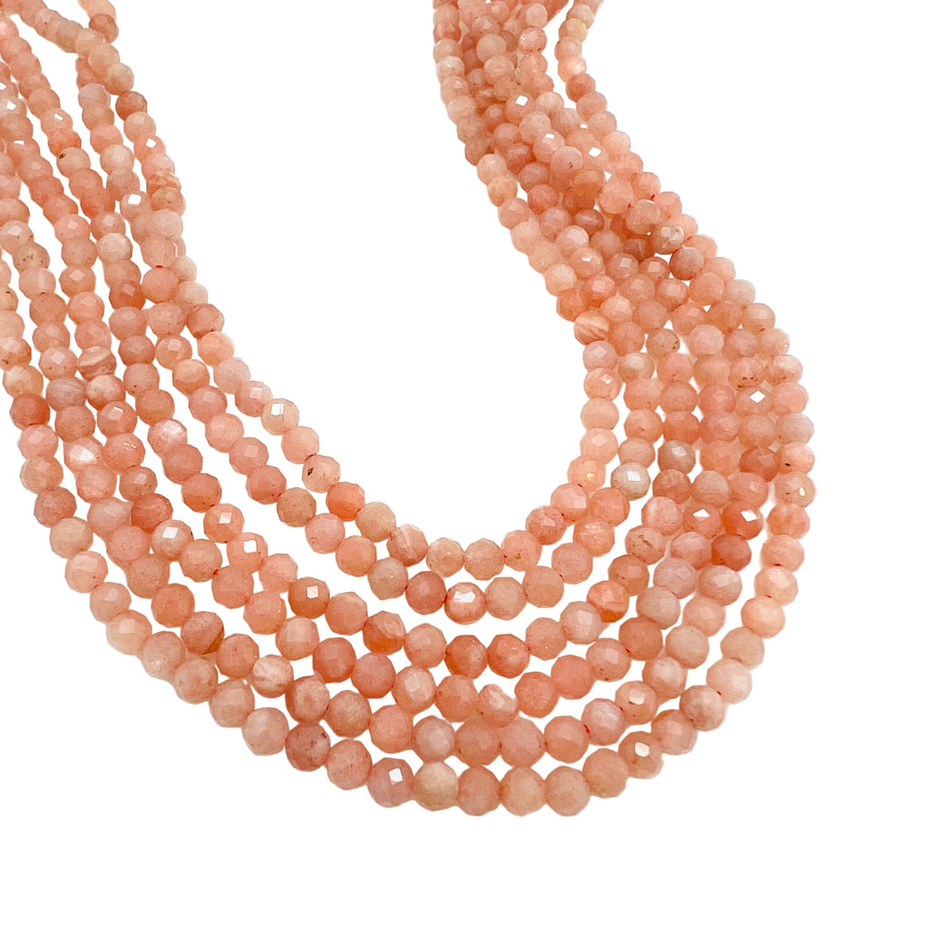 six strands of faceted round sunstone beads over white background. 