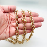 golden large cable chain necklace with toggle clasp on a hand on white background. 