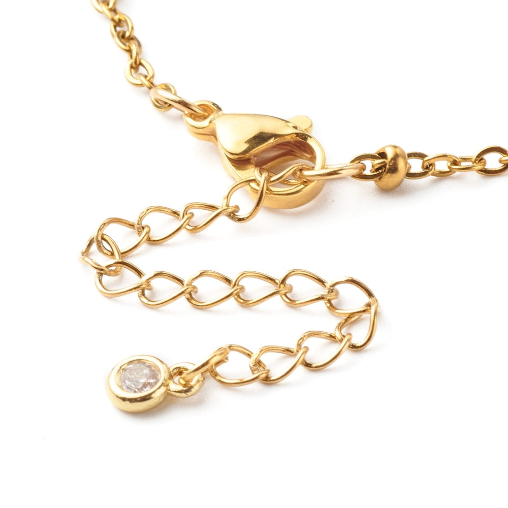 zoomed in lobster claw clasp and extender with bezel set clear stone of golden satellite chain bracelet on white background. 