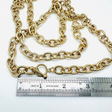 golden large cable chain necklace with toggle clasp above a stainless steel imperial ruler on white background. 