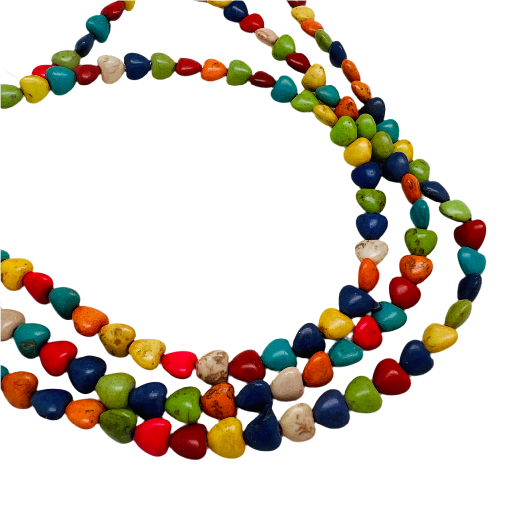 three strands of multicolor dyed magnesite heart stone beads over white background. 