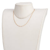 golden chain and purple amethyst faceted round beaded necklace on off-white neck form with white background. 