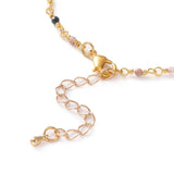 zoomed in section of golden chain and multi-colored tourmaline faceted round beaded necklace with golden lobster claw clasp and extender chain over white background. 