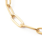 zoomed in section of golden paperclip chain bracelet on a white background.