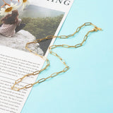 golden medium link paperclip chain necklace with lobster claw clasp on magazine article and light blue background.. 