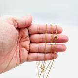 golden fine flat cable chain necklace with lobster claw clasp displayed on a hand with a white background. 