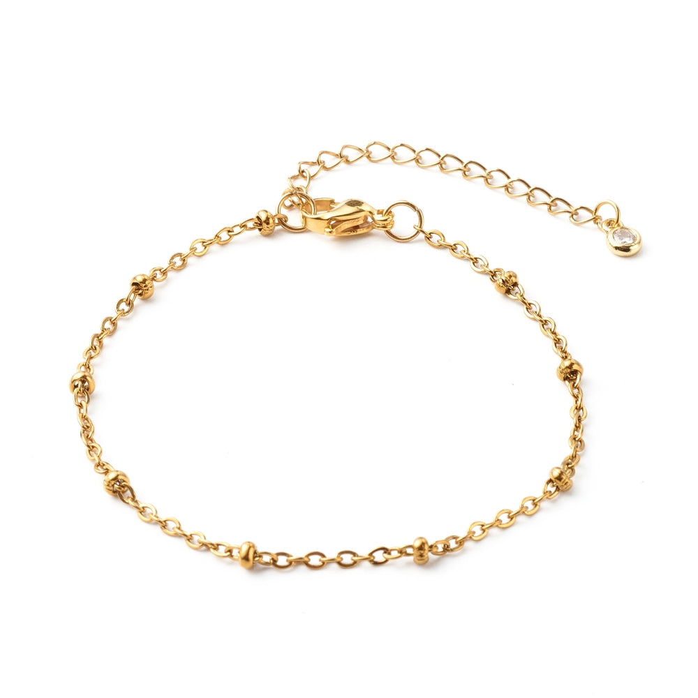 golden satellite chain bracelet with lobster claw clasp and extender chain with bezel set clear stone charm on end on white background. 