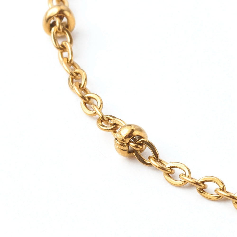 zoomed in section of golden satellite chain bracelet on white background. 