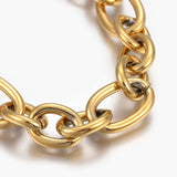 zoomed in section of golden, large alternating oval and round link chain on white background.