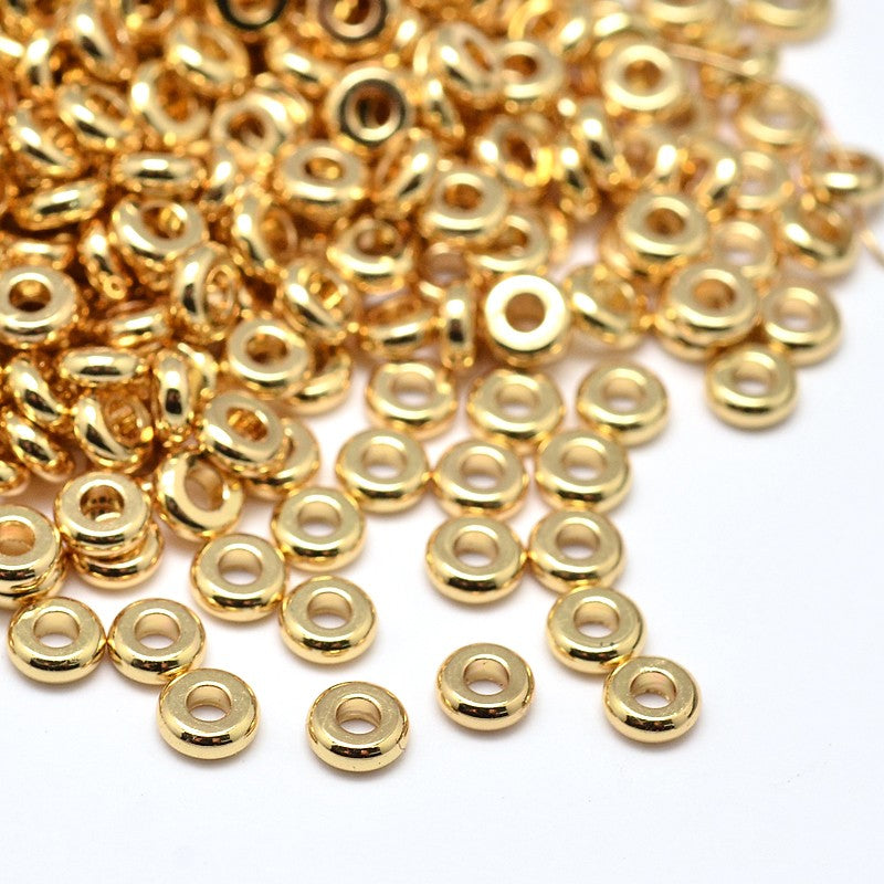 pile of golden rondelle spacer beads over white background. 