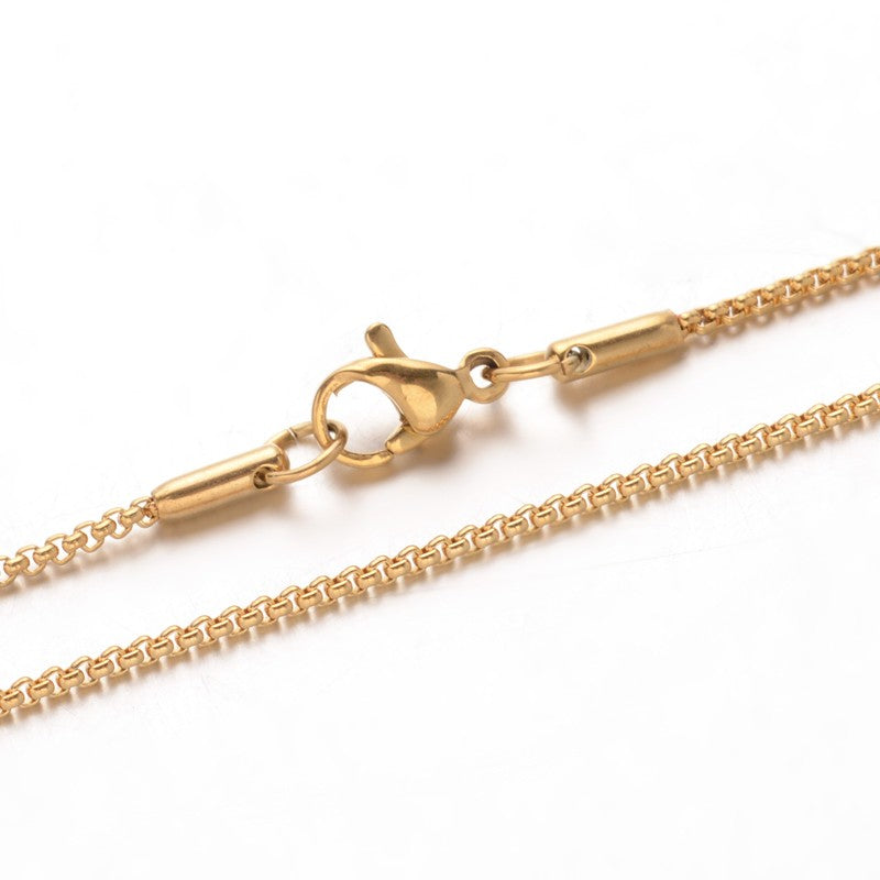 zoomed in sections of golden box chain necklace with lobster claw clasp over white background. 