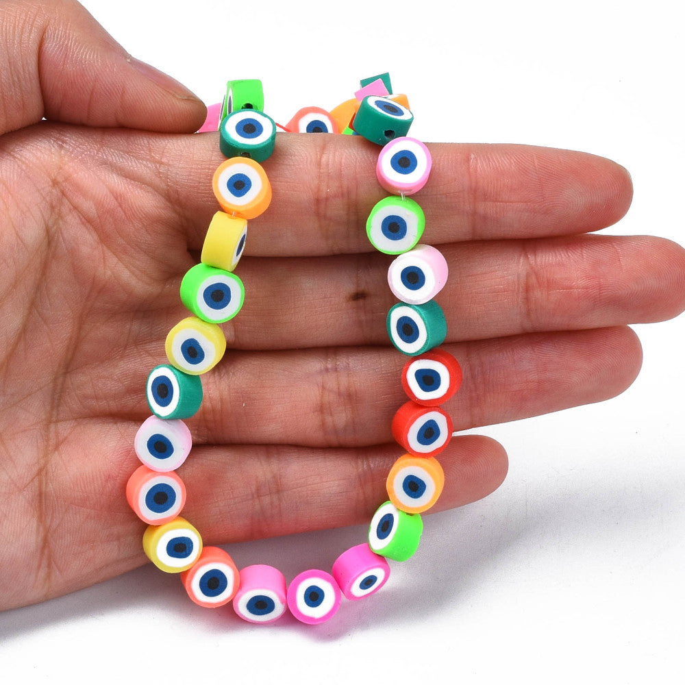 multicolor polymer clay round eye bead strand draped over hand with white background. 