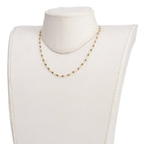 golden chain and black spinel faceted round beaded necklace on off-white neck form with white background. 