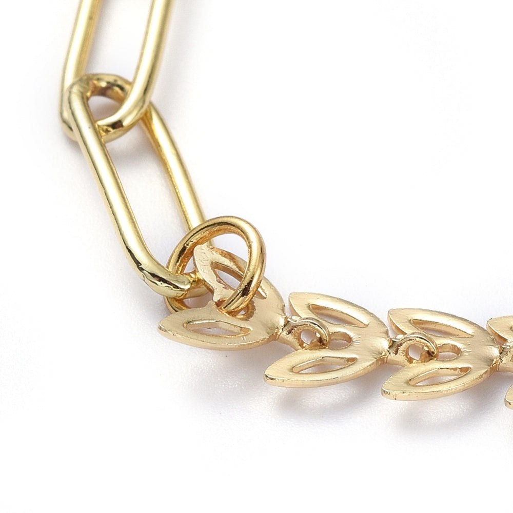 zoomed in section of golden mixed chain necklace with both cob leaf and paperclip links on white background. 