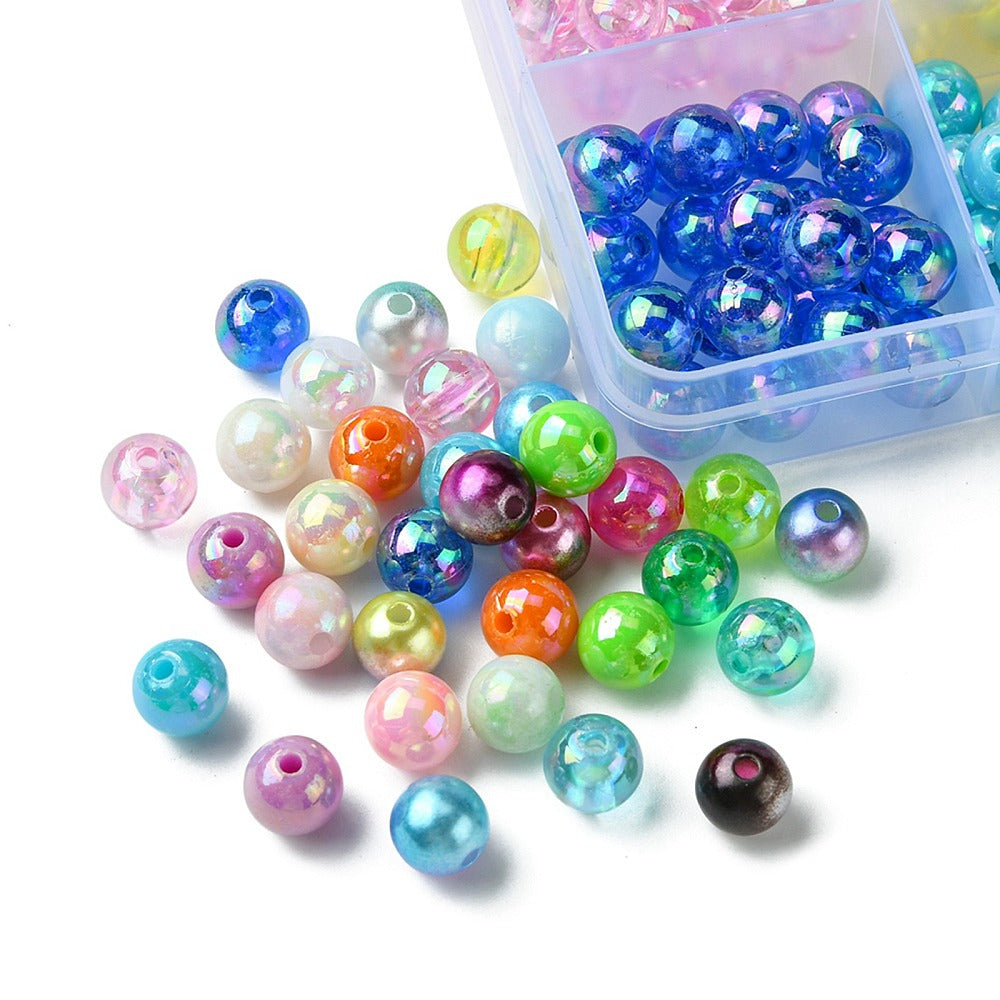 corner of filled plastic bead box with a cluster of the varieties of smooth round beads on a white surface. 