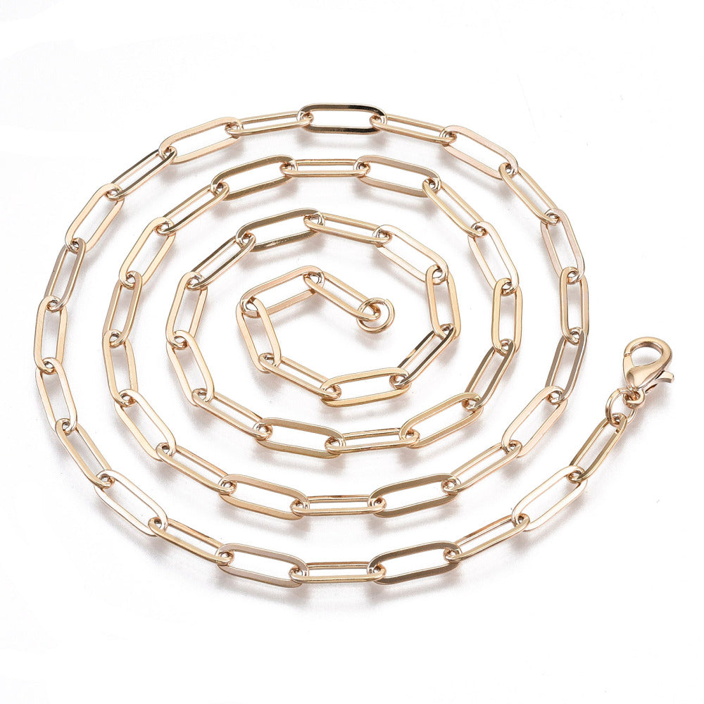 golden small paperclip link necklace with lobster claw clasp in swirl pattern over white background. 