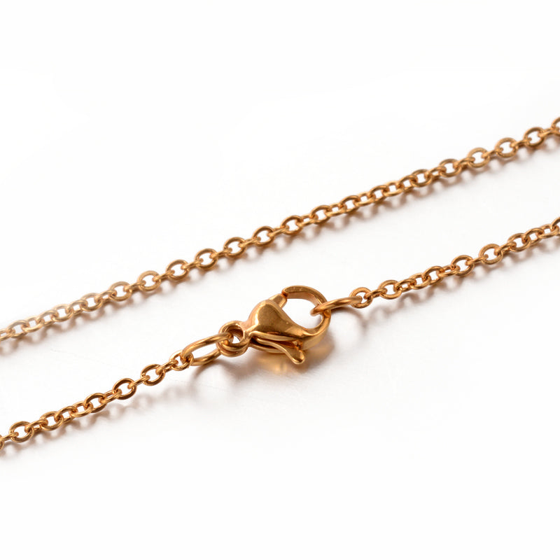 zoomed in section of golden fine flat cable chain necklace with lobster claw clasp on a white background. 