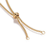 zoomed in portion of adjustable slider bead and two jump rings on golden Venetian box chain against a white background. 