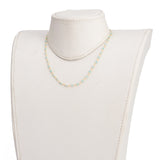 golden chain and turquoise amazonite faceted round beaded necklace on off-white neck form over white background. 