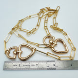 plated brass paperclip link chain with swivel heart clasp near a silver imperial ruler with a white background. 
