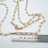 golden medium round oval paperclip chain necklace with lobster claw clasp above stainless steel imperial ruler on white background. 