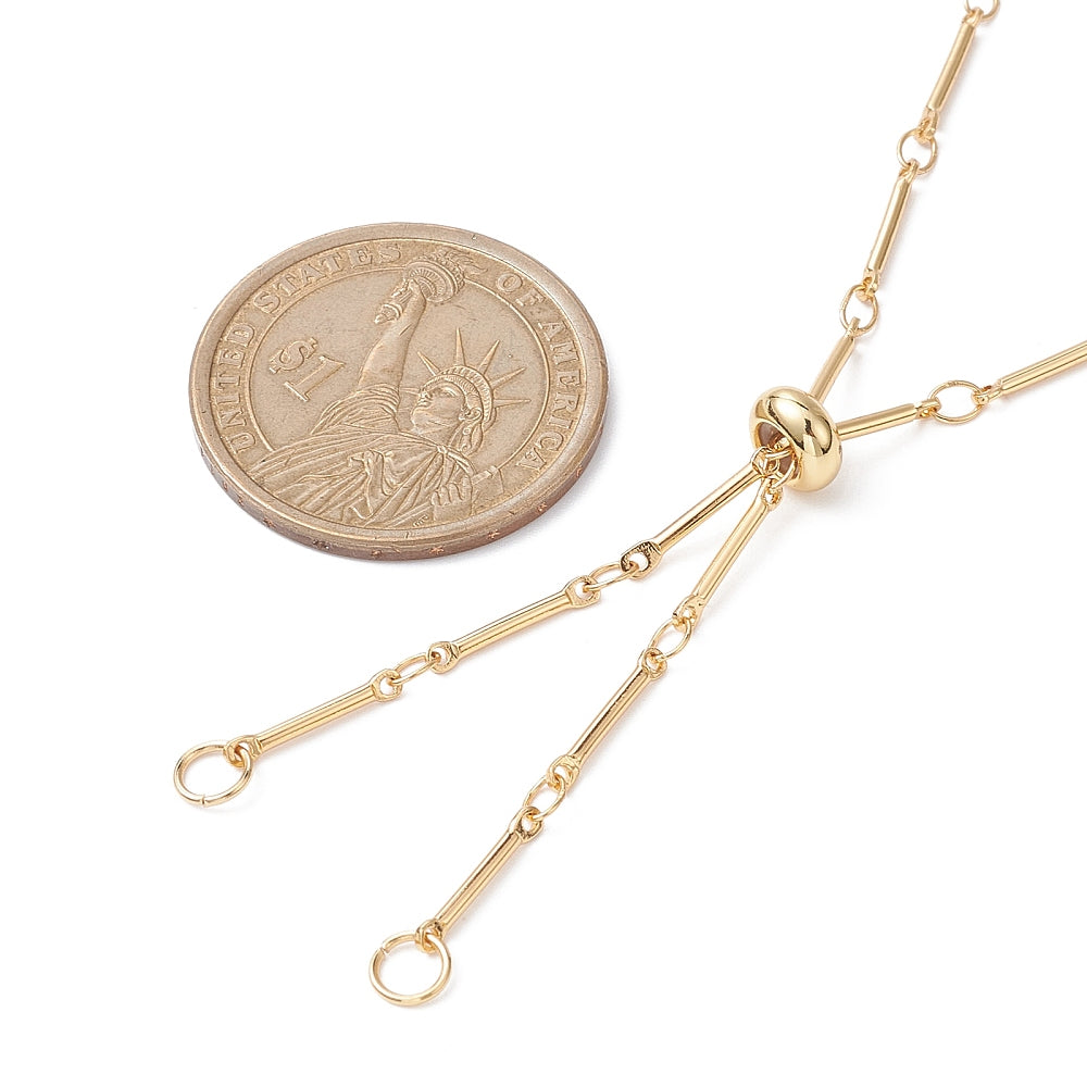zoomed in section of golden bolo style bar link chain necklace with slider bead and two jump rings next to a dollar coin. over white background. 