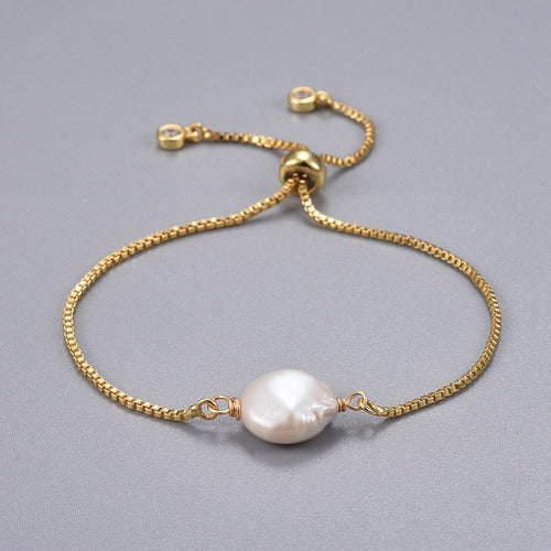 adjustable golden box chain bracelet featuring coin pearl with slider bead and bezel set charms on light grey surface. 