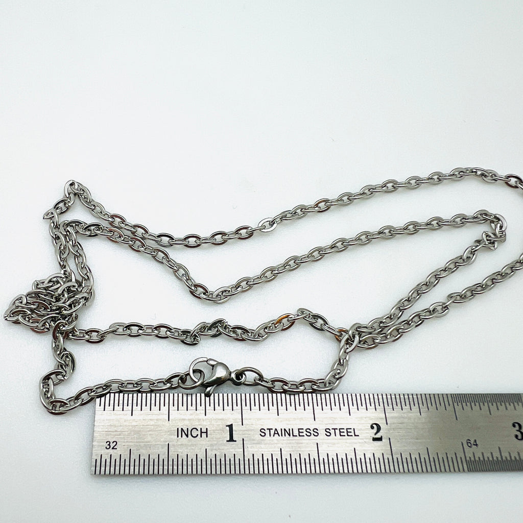 silver tone flat cable chain necklace with lobster claw clasp displayed above a ruler over white background. 