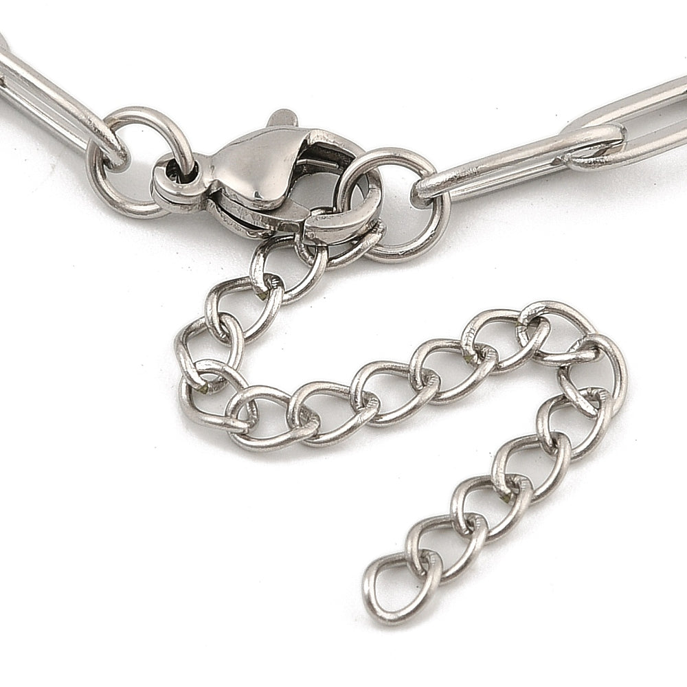 zoomed in section of silver tone paperclip chain bracelet with lobster claw clasp and extender chain over white background. 