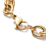 zoomed in section of golden heavy Figaro chain bracelet with lobster claw clasp on white background. 