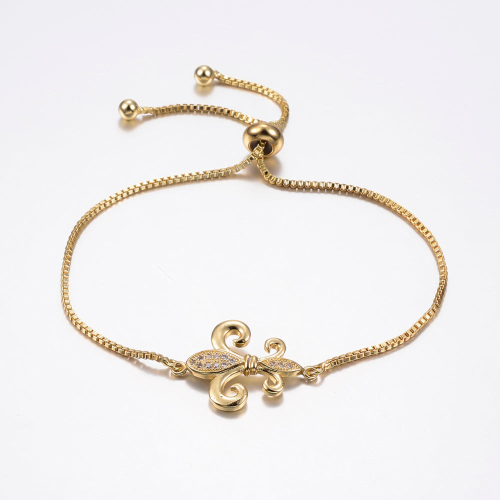 golden, micro pave set clear stone fleur de lis connector and box link bracelet with bolo style adjustable clasp on white background. 