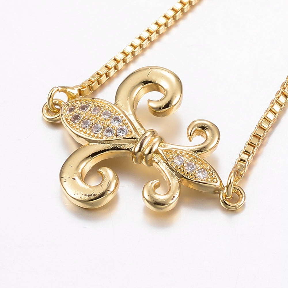 zoomed in micro pave set, clear stone, fleur de lis connector on box link bracelet against white background. 