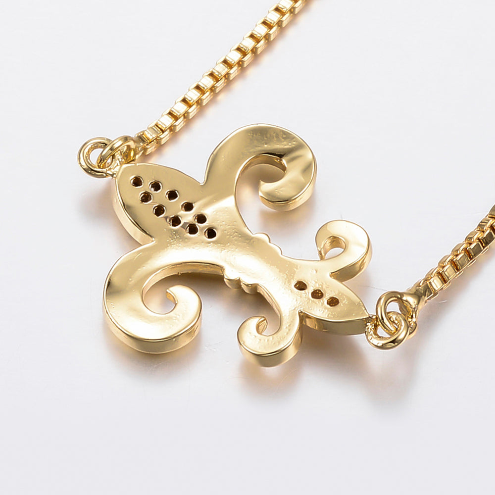 back of golden fleur de lis connector piece on box link bracelet against white background. 