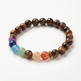 tiger eye chakra bead bracelet featuring seven round chakra stone beads between antique spacer beads over white background. 