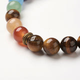 zoomed in section of tiger eye chakra bead bracelet featuring seven round  chakra stone beads between antique spacer beads on white background. 