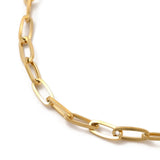 zoomed in section of golden flat paperclip chain bracelet over white background. 