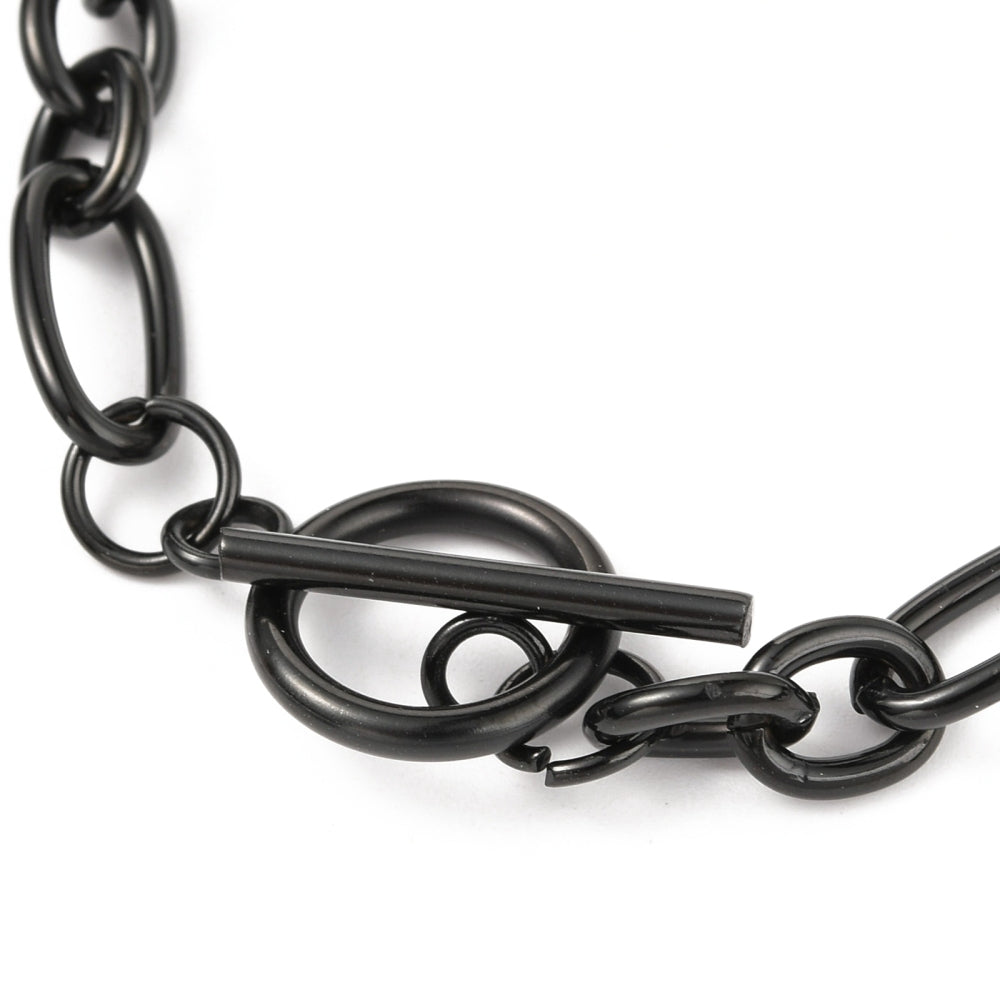 zoomed in black toggle clasp on a Figaro chain bracelet against a white background. 