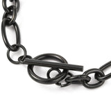zoomed in black toggle clasp on a Figaro chain bracelet against a white background. 