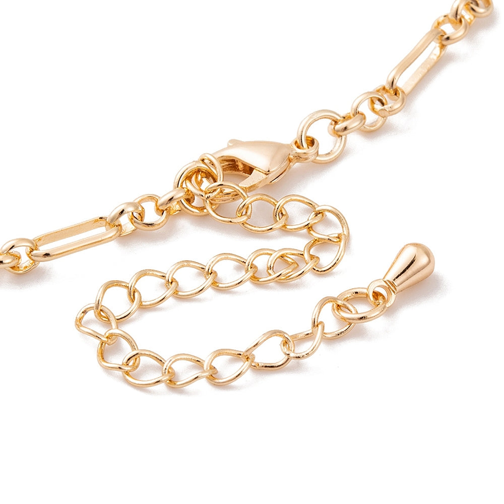 zoomed in section of golden oval Figaro link bracelet with lobster claw clasp and extender chain over white background. 